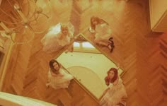 four women dressed in white are sitting on the floor looking at their own selfies