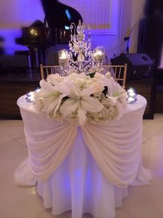 the centerpiece is adorned with white flowers and crystal chandelier at the head table