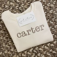 "This adorable sweatshirt is perfect for cool Fall days (or for cold school classrooms). Personalize with a name or initials, or a Fall design. Ecru sweatshirt is made from soft 100 percent combed cotton.  \"Carter\" is type font in khaki thread - all lowercase letters" Cream Cotton Sweatshirt With Letter Embroidery, Personalized Cotton Sweatshirt For Winter, Personalized Cotton Crew Neck Sweatshirt, Customizable Crew Neck Sweatshirt For School, School Crew Neck Sweatshirt With Name Print, Cream Crew Neck Sweatshirt With Letter Embroidery, White Cotton School Sweater, Personalized Cotton Sweatshirt For Fall, White Letter Embroidery Sweatshirt For School