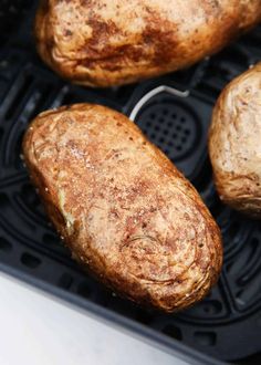 three cooked potatoes sitting on top of an air fryer