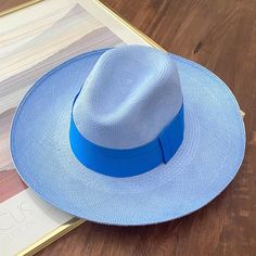 The Azulu’s pastel blue straw is given a playful color pop with its turquoise Toquilla straw band. We took our favorite hat and made it with a 4 inch wide brim. Handmade in Ecuador from 100% Toquilla straw Shape: 'Clasico' Panama hat Color: Baby Blue / Turquoise Band Size-adjustable inner band Chic Blue Beach Hat, Blue Flat Brim Sun Hat For Beach, Chic Blue Straw Hat For The Beach, Blue Summer Panama Hat For Beach, Blue Flat Brim Boater Hat For Beach, Blue Panama Hat For Beach With Curved Brim, Blue Panama Hat With Curved Brim For Beach, Blue Boater Hat With Curved Brim For Beach, Blue Wide Brim Fedora For Kentucky Derby