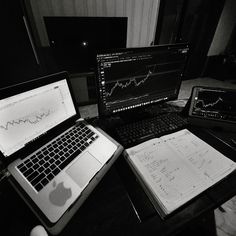 two laptops and a computer monitor on a desk in front of each other with graphs