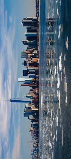 an aerial view of the city skyline from across the water, looking up at skyscrapers