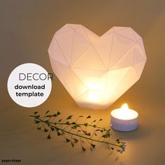 a white candle next to a heart shaped paper lantern with the words decor on it