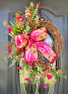 a wreath on the front door decorated with pink and orange flowers