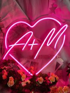 a pink neon sign that reads 4 + 0 with flowers in the foreground and newspaper behind it