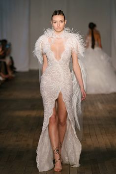 a model walks down the runway in a white dress with feathers on it