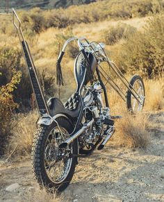 a black motorcycle parked on top of a dirt field