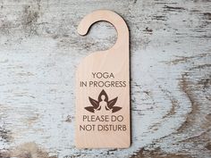 a wooden door hanger that says yoga in progress please do not disturb