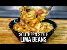 a spoon full of food sitting on top of a wooden table with the words southern style lima beans