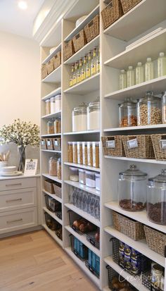 an organized pantry with white shelving and wicker baskets on the bottom shelfs