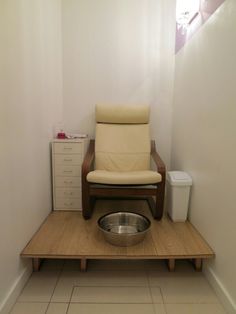 a chair sitting on top of a wooden platform next to a metal bowl and toilet