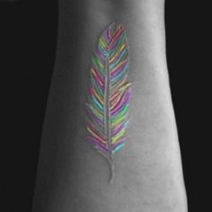 a colorful feather tattoo on the wrist