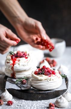 someone is spreading cranberry sauce on top of the whipped cream cake with berries