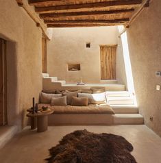 a living room filled with lots of furniture next to a stone wall and wooden beams