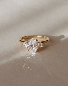 a three stone diamond ring on a white surface with the light shining through it's reflection