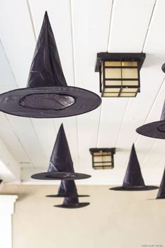 several black witches hats hanging from the ceiling in a room with white walls and ceilings