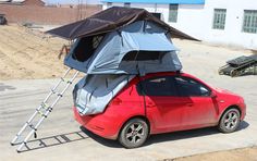 a red car parked in front of a building with a tent attached to the roof