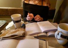 a woman sitting at a table with an open book and coffee cup in front of her