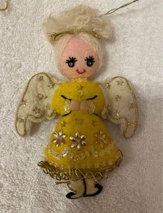 an angel ornament is hanging on a white towel with gold sequins