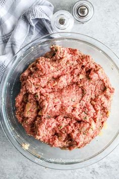 a glass bowl filled with ground meat on top of a table