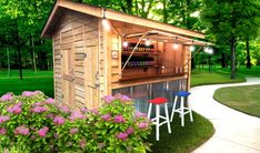 an outdoor bar with three stools next to it and flowers in the foreground