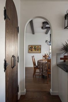 an archway leading to a dining room with a table and chairs next to it on top of a hard wood floor