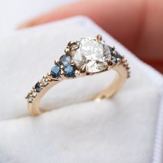 a ring with blue and white stones in it sitting on top of a cloth bag