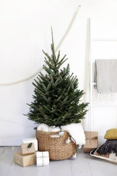 a small christmas tree sitting in a basket next to other presents and blankets on the floor