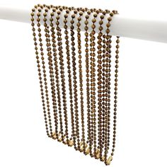 a long beaded curtain hanging from a white pole with gold colored beads on it