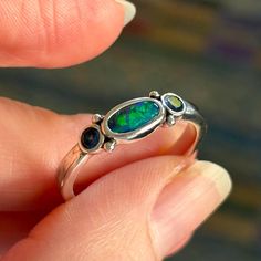 I am selling an Australian Black opal and sapphire sterling silver ring from my collection. It is stamped 925 inside. The ring is in good condition and shows just typical scuffing of the sterling from being worn. There are no scratches to the stones. Light cornflower blue sapphires are 0.27ct total. Ring is a size 10. The opal is solid opal. Sterling Silver Multi-stone Opal Promise Ring, Multi-stone Sterling Silver Opal Ring, Oval Multi-stone Opal Ring In Sterling Silver, Sterling Silver Cabochon Opal Ring For Anniversary, Sterling Silver Opal Ring With Cabochon For Anniversary, Silver Three Stone Opal Ring For Anniversary, Sterling Silver Multi-stone Opal Ring, Sterling Silver Opal Ring With Multi-stone Design, Sterling Silver Opal Anniversary Ring