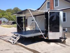 an enclosed trailer parked in front of a house on the side of a road with stairs leading up to it