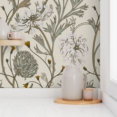 a white vase sitting on top of a counter next to a wallpaper covered in flowers