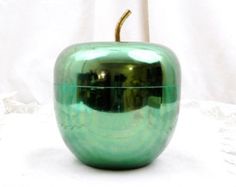 a shiny green apple sitting on top of a white table