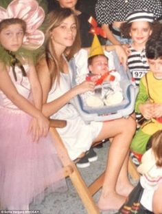 a group of people sitting around each other in front of a tree with hats on