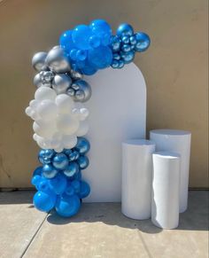 blue and silver balloons are on display in front of a white arch with two vases