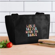 a black bag with the words life is better when you dance on it next to a sandwich