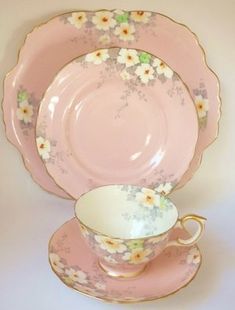 a pink china tea cup and saucer with flowers on the rim, sitting next to each other