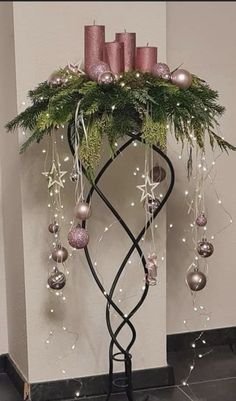 a christmas tree with candles and ornaments hanging from it's branches in front of a wall