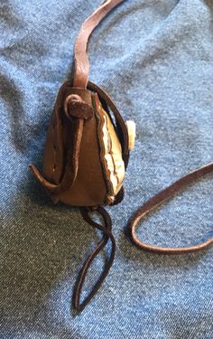 an old purse is sitting on a blue cloth with a brown leather strap around it