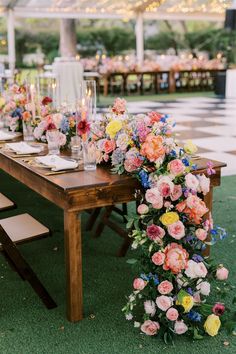 a long table with flowers and candles on it is set up for an outdoor dinner