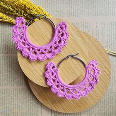 two pairs of crocheted hoop earrings sitting on top of a piece of wood