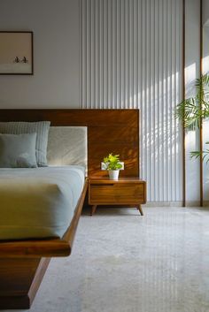 a bedroom with a bed, nightstand and potted plant