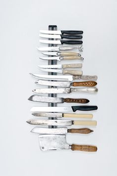 a bunch of knives are lined up on a white surface with one knife stuck in the middle