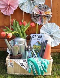 a garden box filled with gardening tools and flowers next to a wooden fence covered in paper umbrellas