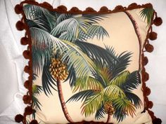 a decorative pillow with palm trees and pom - poms on the bottom, sitting on a bed