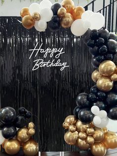 black and gold balloons are arranged in the shape of a happy birthday arch on display