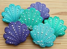 three decorated cookies sitting on top of a wooden table next to each other with pearls