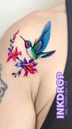 a hummingbird on the back of a woman's shoulder with flowers and leaves