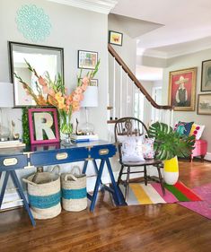 a living room filled with lots of furniture and pictures on the wall next to a stair case